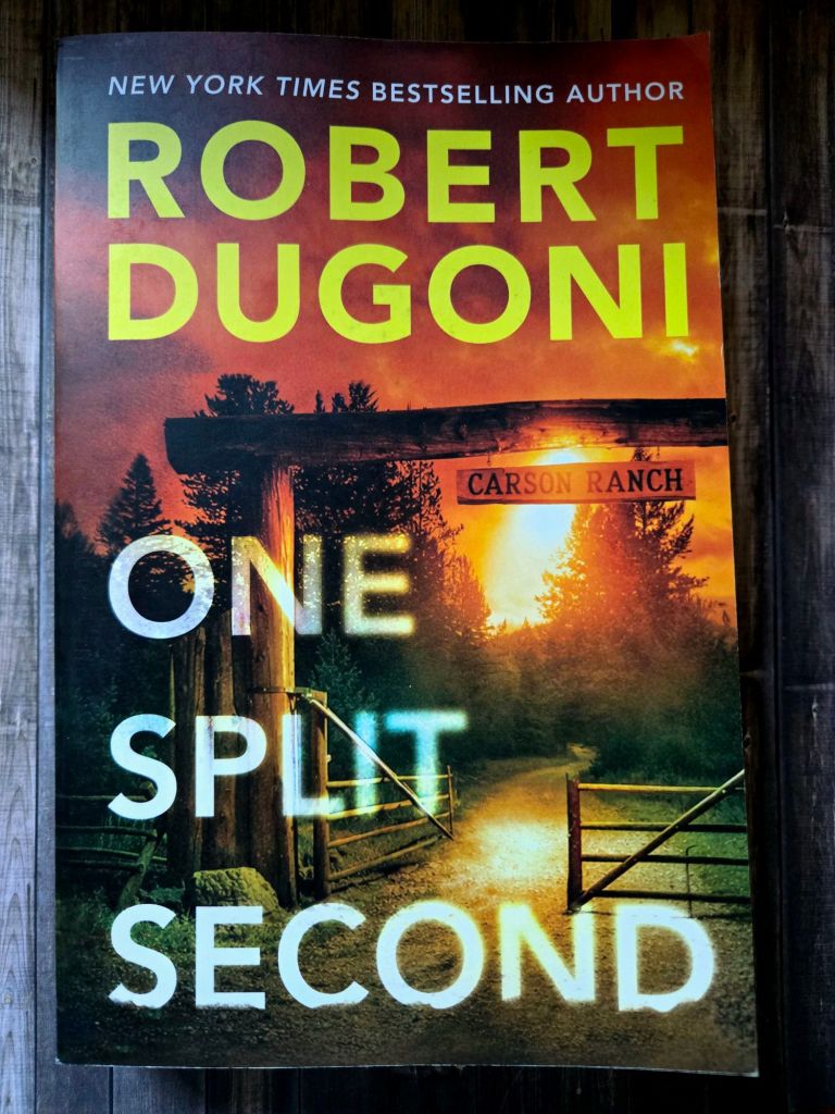 Cover of the book 'One Split Second' by Robert Dugoni featuring a scenic image of a ranch with a pathway and sunset.